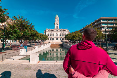 Rear view of man outside building against sky