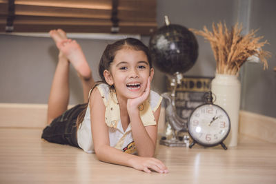 Full length portrait of cute cheerful girl lying on floor at home