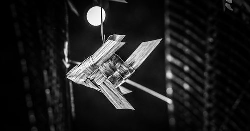 Low angle view of illuminated light bulb hanging at night