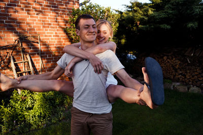 Young man carrying woman on back in backyard