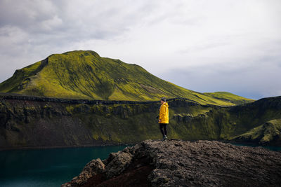 Rear view of man standing on mountain against sky