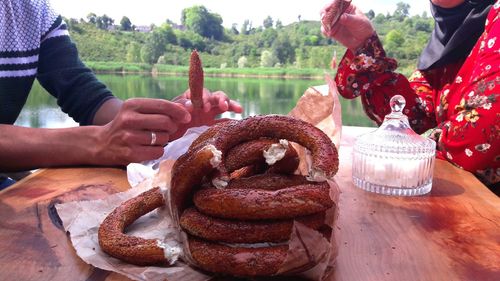 Midsection of couple eating food on table against lake