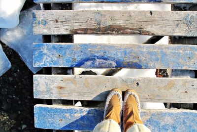 Low section of person standing on wooded footbridge