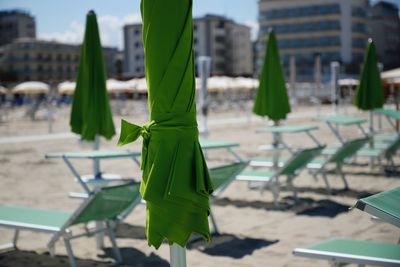 Green parasoo on chair at beach against sky