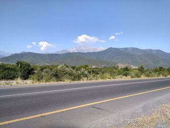 Road by mountains against sky