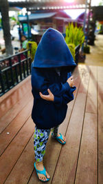 Boy wearing hooded shirt while standing on boardwalk