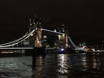 Illuminated suspension bridge over river at night