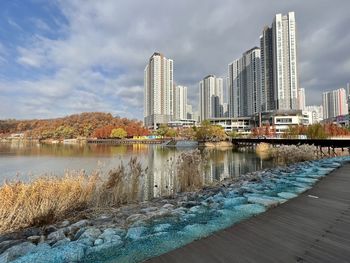 Buildings by lake against sky in city