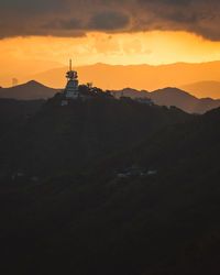 Scenic view of silhouette mountains against orange sky