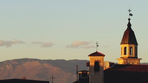 Church amidst buildings against sky during sunset