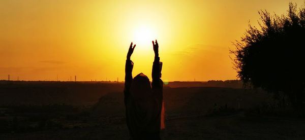 Silhouette person standing on field against sky during sunset