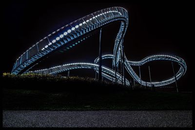 Illuminated ferris wheel against sky at night