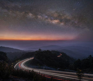 Light trails on road against sky at night