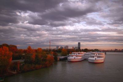 Boats in city against cloudy sky