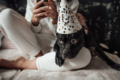 Midsection of woman with dog relaxing at home