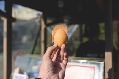 Close-up of hand holding egg shaped pastry