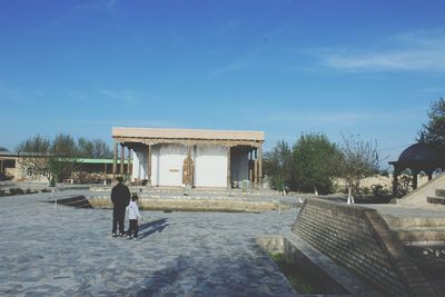 Rear view of people walking against blue sky