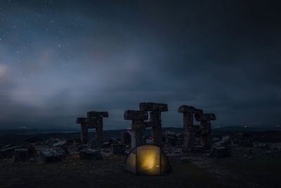 Tent by abandoned built structure against sky at night