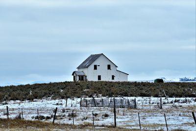 House on field by building against sky