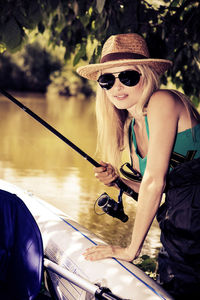 Portrait of mid adult woman wearing sunglasses fishing while canoeing on lake