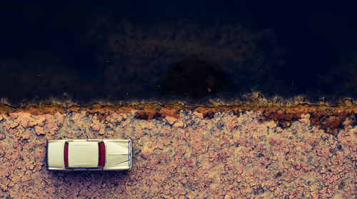 Directly above shot of vintage car parked by river