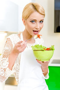 Portrait of smiling young woman eating food at home