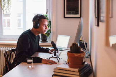 Side view of young freelance worker using computer at desk