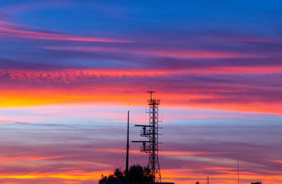 Low angle view of silhouette electricity pylon against sky during sunset