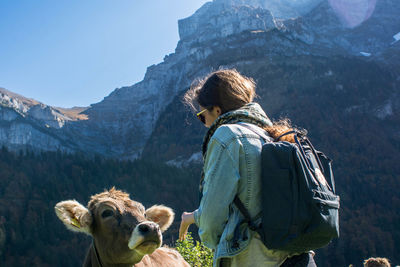 Female hiker standing with cow against mountains