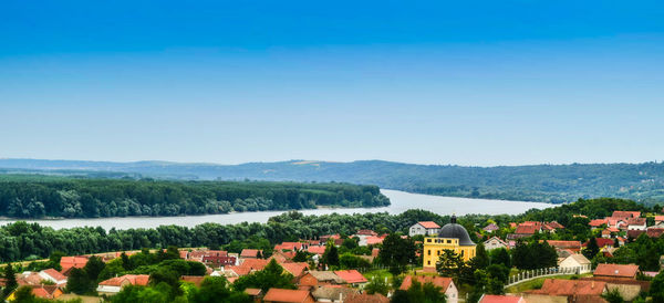 High angle view of houses in town against clear blue sky