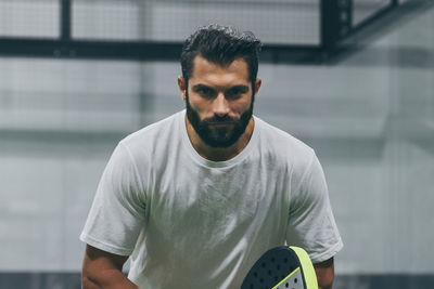 Man playing paddle tennis, racket in hand concentrated look. young sporty boy ready for the match.