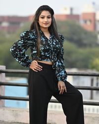 Portrait of young woman standing against railing