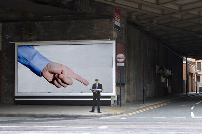 Man standing on road by building
