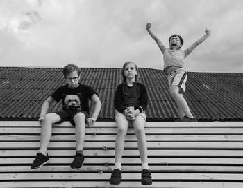 Portrait of friends sitting against sky