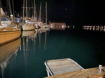 Sailboats moored in harbor at night