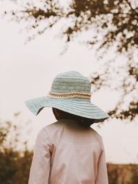 Rear view of girl in hat standing against sky