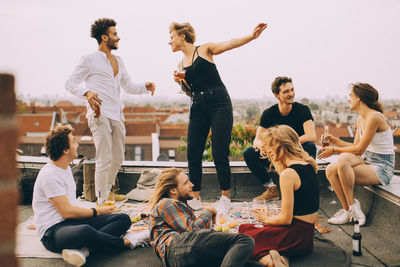 Happy people dancing while enjoying music with friends on terrace at rooftop party