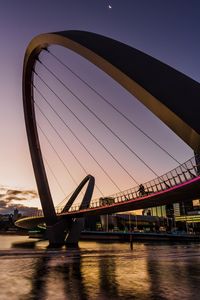 Bridge over river against clear sky at sunset