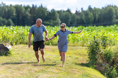 Romantic middle-aged couple holding hands running in the garden, the concept of a happy relationship