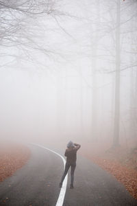 Rear view of woman standing on road in foggy weather