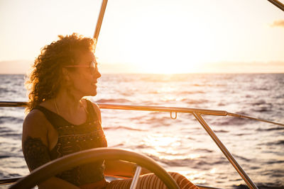 Woman sitting on boat in sea against sky