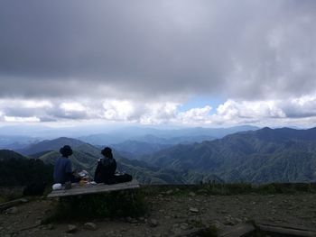 People sitting on mountain against sky