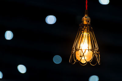 Low angle view of illuminated light bulb against sky at night