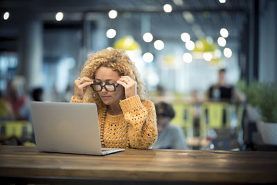 Woman using laptop on table while sitting in cafe