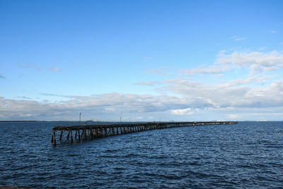 Pier over sea against blue sky