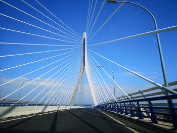 Low angle view of suspension bridge against blue sky