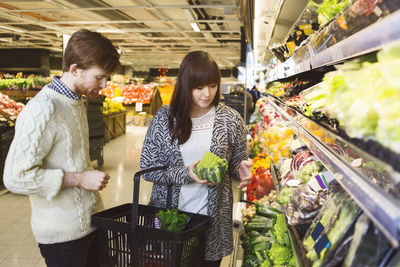 Young couple buying vegetables at supermarket