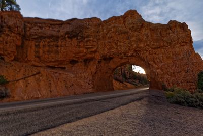 Road leading towards rock formation against sky