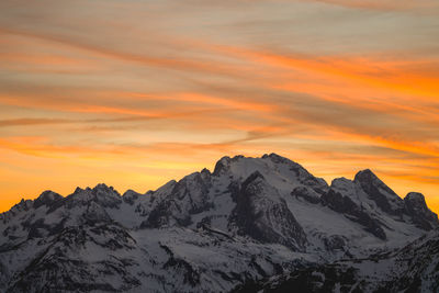 Scenic view of snowcapped mountains against orange sky