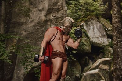 Full length of shirtless man holding rock